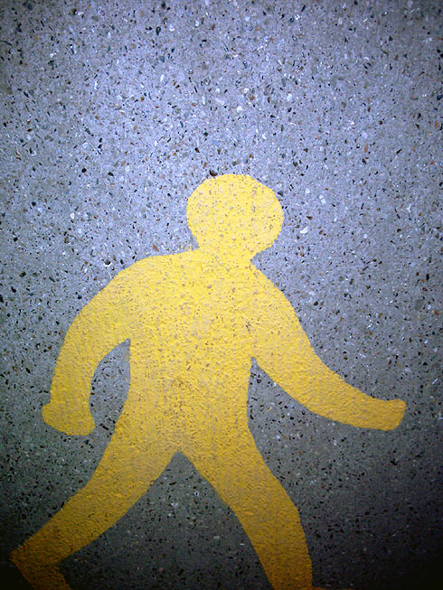 Yellow pedestrian symbol painted on tarmac