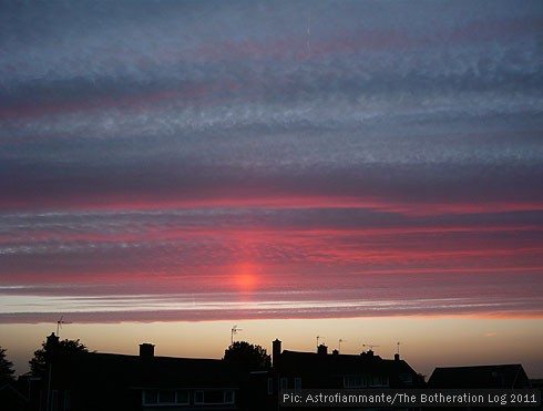 Sun setting behind high-level cloud and rooftops