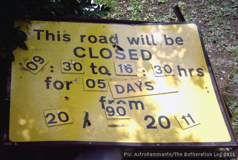 A sign announcing a road closure with jumbled letters and numbers