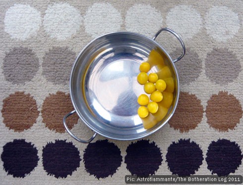 A circular bowl of plums on a mat decorated with circles