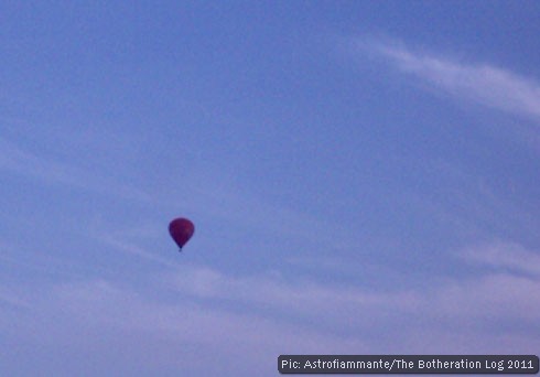 Distant hot air balloon in near-cloudless blue sky