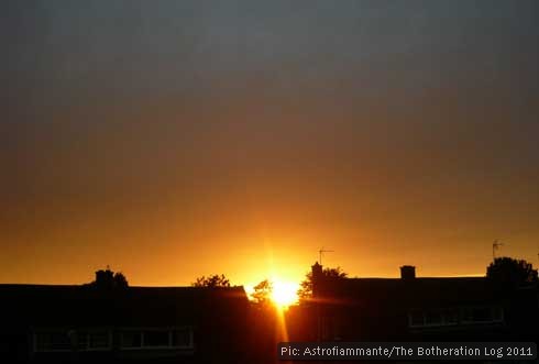 Sun sinking behind rooves