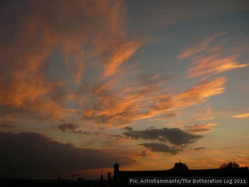 Orange-gold and grey clouds at sunset against a dark-blue sky