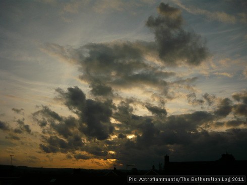 Dark grey clouds against a blue and orange sunset sky