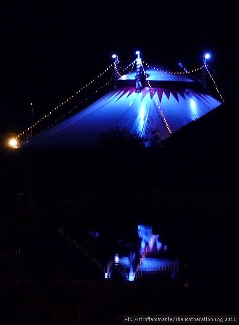 Circus marquee after dark, reflected in nearby swimming pool