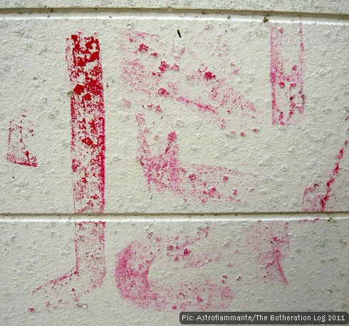 Faded red paint lines on a white-painted breezeblock wall