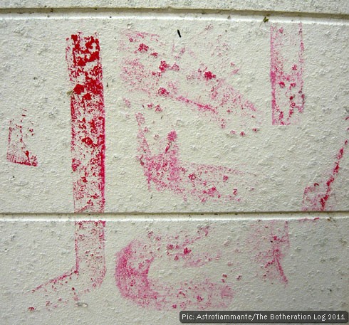 Faded red paint lines on a white-painted breezeblock wall