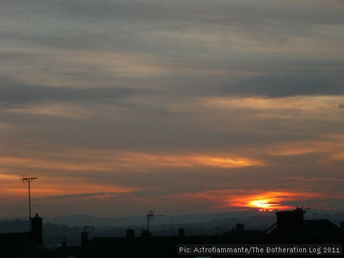 Sun dropping below horizon of hills and TV aerials