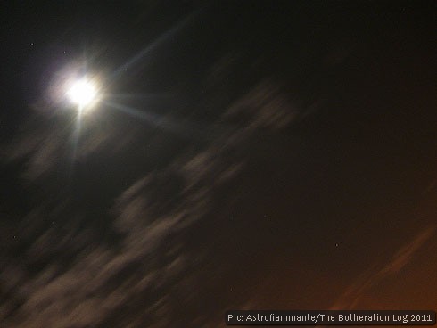 Long-exposure night photograph showing moon, clouds and streetlight glow