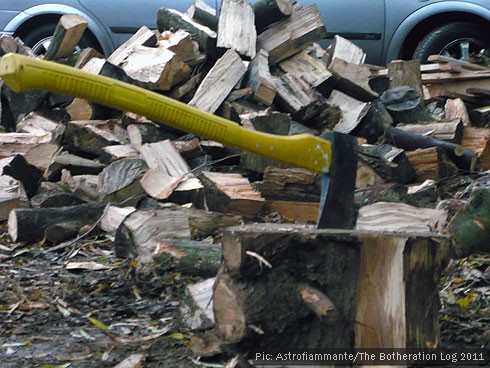 Yellow-handled axe stuck in stump surrounded by chopped firewood