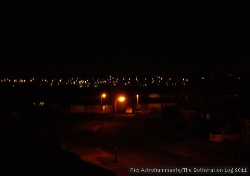 Street scene at night with streetlamps in the foreground and in the far distance