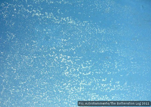 Ice crystals on a roof window with a blue sky behind them