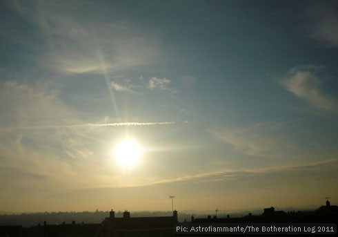 The sun dropping from a blue sky to a cloudbank