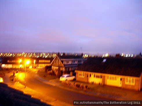 Long-exposure photograph of suburban street after dark.