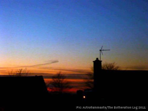 Strongly blue and orange sunset over dark roofline