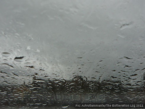 Raindrops on a window pain obscuring a gloomy street scene