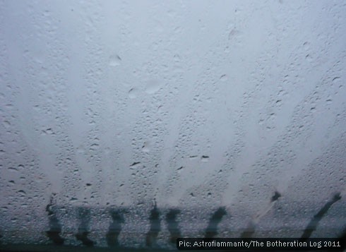 Raindrops on a windowpane with a grey sky behind