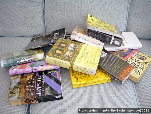 A heap of library books on a sofa