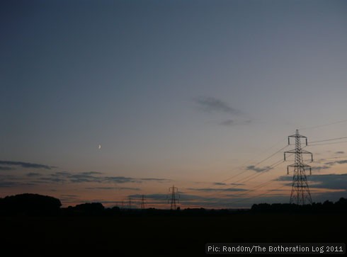A line of transmission towers (pylons) sillhouetted against the evening sky