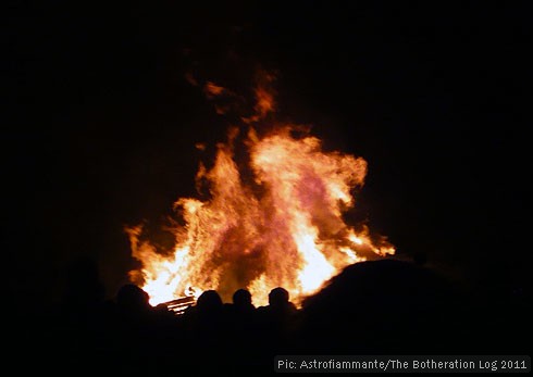 Visitors to a firework display sillhouetted against the bonfire