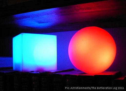 Two novelty coloured lights, one red and one turquoise-blue, on a bookshelf